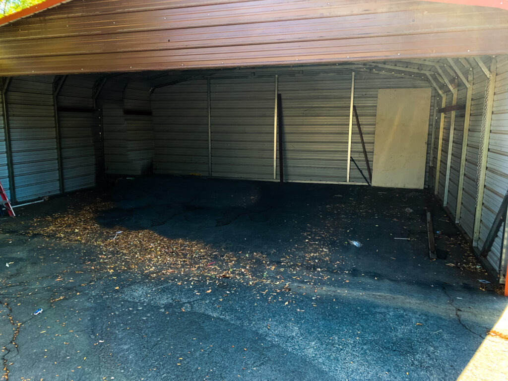 The photo is a close up of the interior and 3 sides of a carport with an open front. 