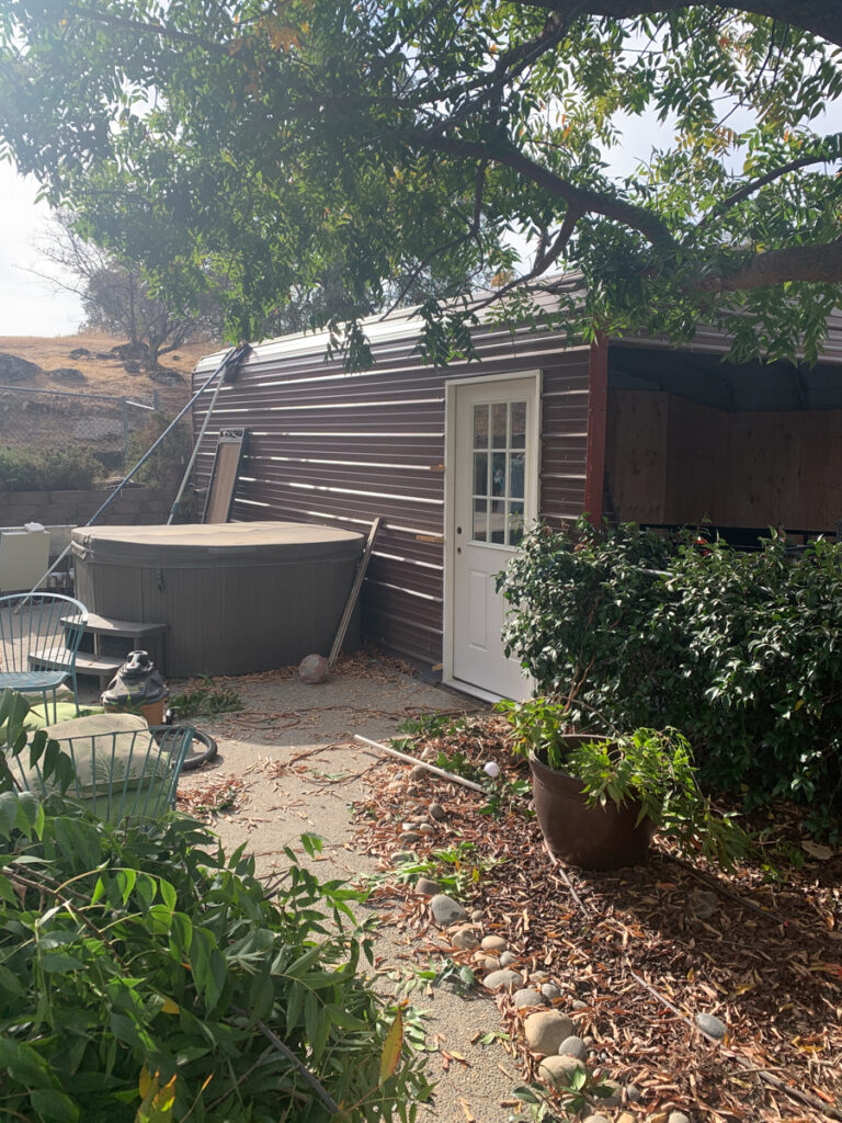 The photo shows the side of the carport with a pedestrian door leading to the interior of the carport barn