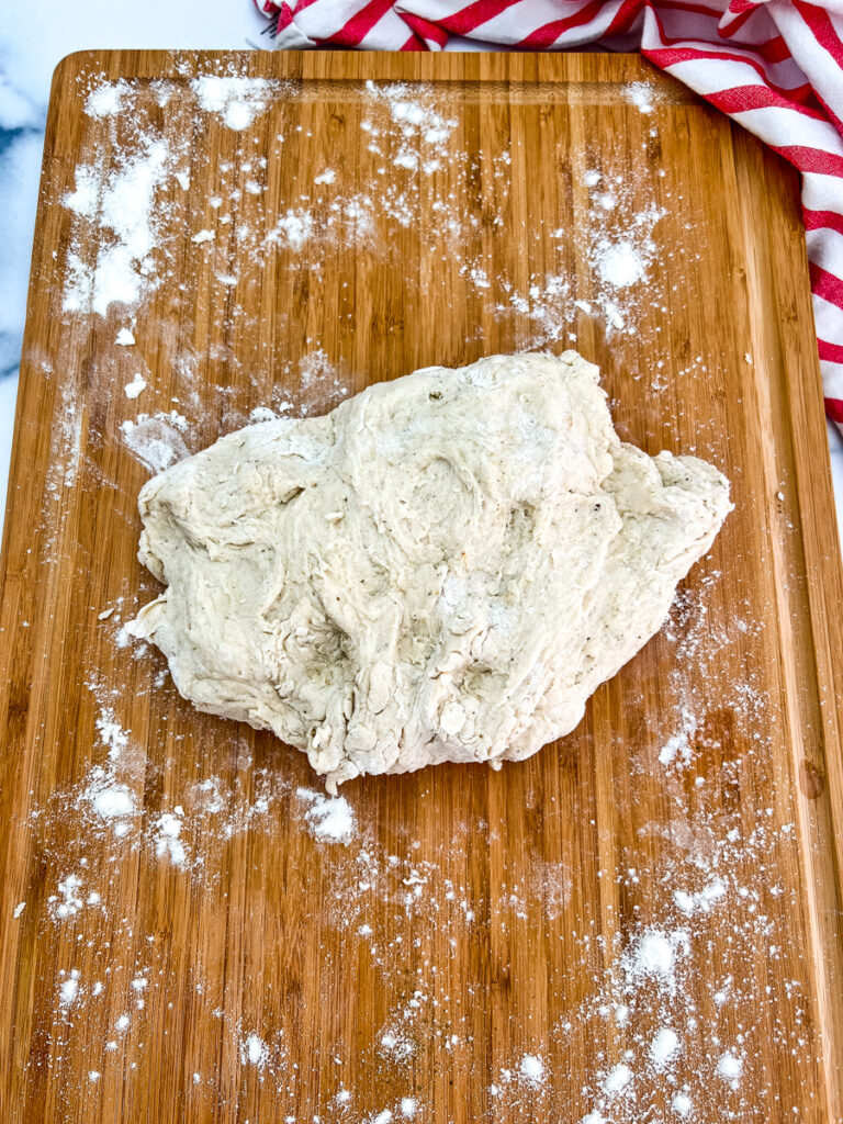 The photo shows dough on a floured cutting board ready to knead.